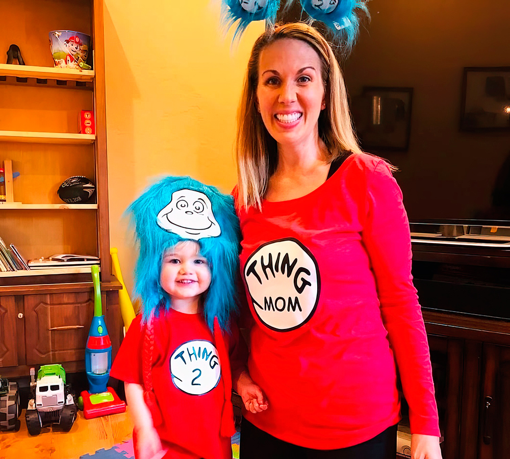 A teacher and child dress up playfully costumes with fun hats, spreading smiles.
