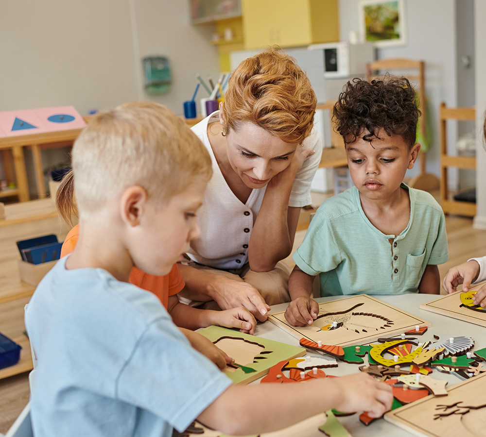 An teacher is helping a few children with a craft project, as they work together, showing concentration and collaboration.