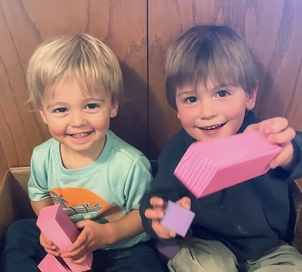 Two smiling boys are happily playing with pink building blocks, showcasing their joy and camaraderie.